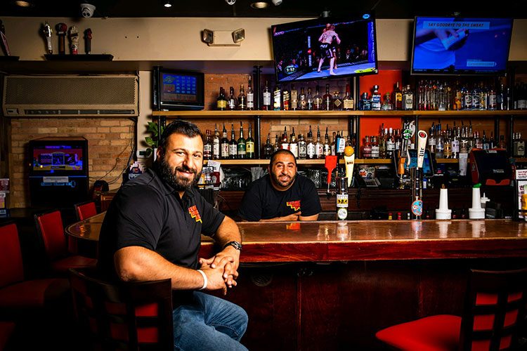 The Basement Burger Bar team at the bar, with the stocked back bar, beer taps and TVs behind them